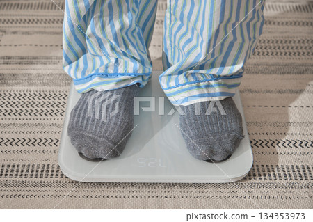 Person weighing on scale making new year resolutions Person weighing on scale making new year resolutions 134353973