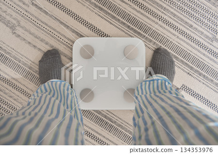 Person standing on smart scale planning new year resolution Person standing on smart scale planning new year resolution 134353976