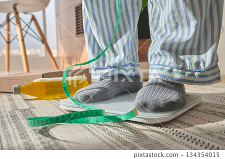 Person standing on scale measuring weight for new year resolution Person standing on scale measuring weight for new year resolution 134354015