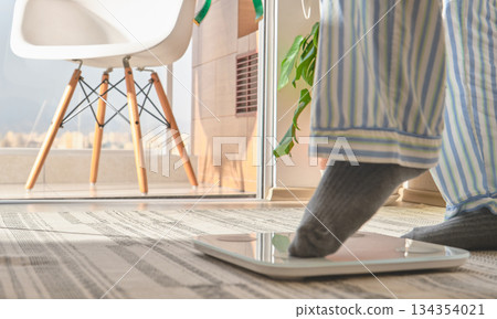 Person weighing on scale making new year resolutions 134354021