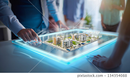 Real Estate Development Vision on a Digital Platform. A businessman interacts with a digital tablet displaying a 3D model of a real estate development, featuring modern apartment buildings, trees, and 134354088