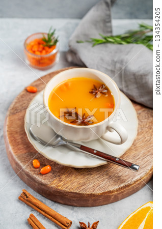 Sea buckthorn herbal tea in a cup on a wooden board on a light background 134354205