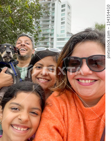 A family of four posing for a picture with a dog A family of four posing for a picture with a dog 134354410