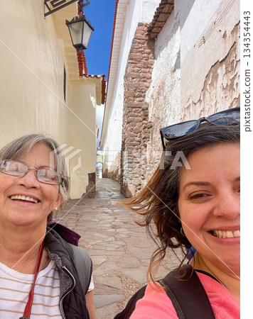 Two women smiling for a photo in a narrow alleyway 134354443
