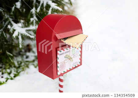 Festive Mailbox. A red mailbox with a letter to Santa in a snowy outdoor setting. Festive Mailbox. A red mailbox with a letter to Santa in a snowy outdoor setting. 134354509
