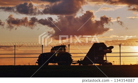 Tractor towing ground support equipment at sunset near airport fence 134354887