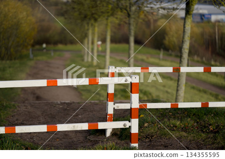 Wrought metal barrier limits passage on shaded park walk Wrought metal barrier limits passage on shaded park walk 134355595