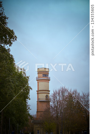 Weathered brick water tower stands tall among vibrant trees and sky 134355605