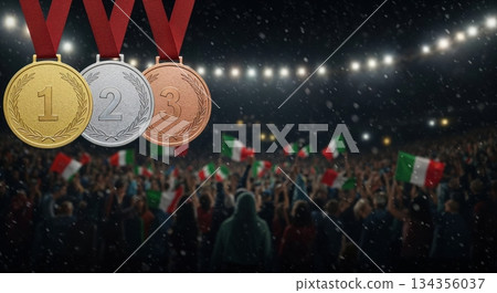 Gold, silver, and bronze medals with red ribbons hang above a cheering crowd waving Italian flags in a brightly lit stadium at night. 134356037