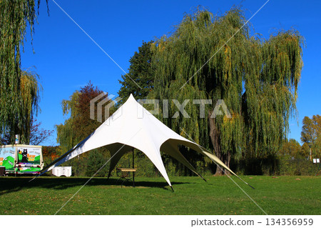 Large white tent set up for an outdoor event in a sunny park with green grass Large white tent set up for an outdoor event in a sunny park with green grass 134356959