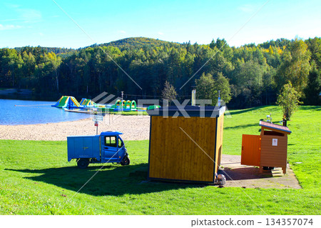 Bright sunny day at a lakeside park featuring inflatable attractions and wooden Bright sunny day at a lakeside park featuring inflatable attractions and wooden 134357074