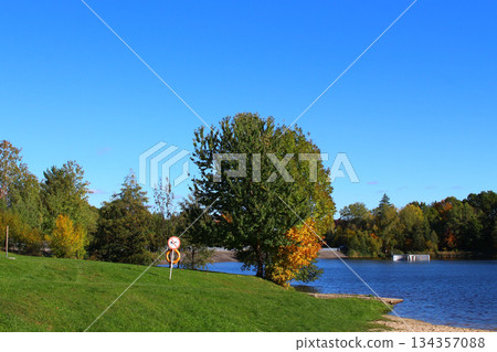 Scenic lakeside view with colorful trees and clear blue sky during autumn 134357088