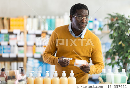 Man in glasses attentively carefully selects pills in modern pharmacy Man in glasses attentively carefully selects pills in modern pharmacy 134357631