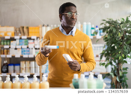 African man choose buy pain relief ointment at pharmacy 134357639