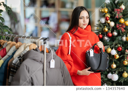 Young woman choosing handbag in store Young woman choosing handbag in store 134357640