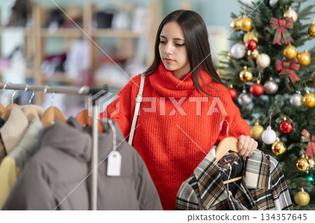 Young girl choosing coat or jacket in clothing store Young girl choosing coat or jacket in clothing store 134357645