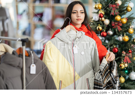 Young girl choosing coat or jacket in clothing store Young girl choosing coat or jacket in clothing store 134357673
