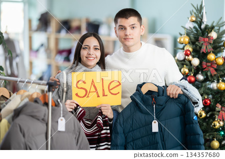 Young couple holding sale sign in clothing store 134357680