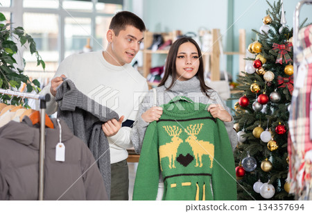 Young couple choosing sweater in store Young couple choosing sweater in store 134357694