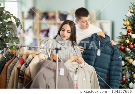 Young couple choosing coat or jacket in clothing store 134357696