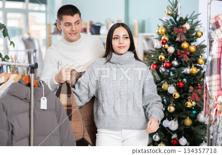 Young couple choosing coat or jacket for girl in clothing store Young couple choosing coat or jacket for girl in clothing store 134357718