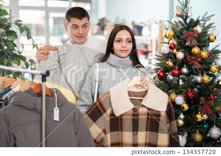 Young couple choosing coat or jacket in store 134357720