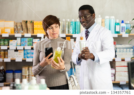 Woman buyer scans shampoo or shower gel qr code with pharmacist Woman buyer scans shampoo or shower gel qr code with pharmacist 134357761