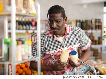 Adult man choosing mayonnaise in grocery store Adult man choosing mayonnaise in grocery store 134357762