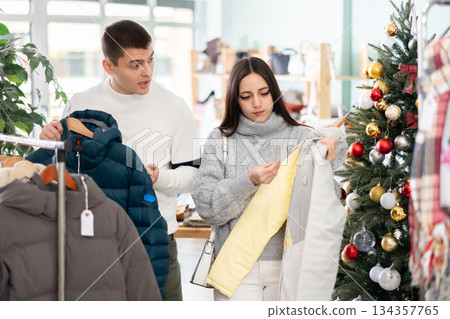 Young couple chooses down jackets in store 134357765