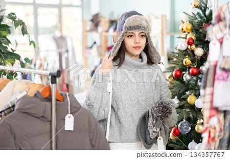 Young girl choosing winter hat in clothing store 134357767