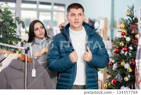 Guy choosing a jacket next to a young woman in a clothing store Guy choosing a jacket next to a young woman in a clothing store 134357784