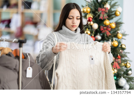 Young woman chooses sweater in clothing store Young woman chooses sweater in clothing store 134357794