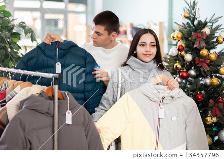 Young couple chooses down jackets in store 134357796