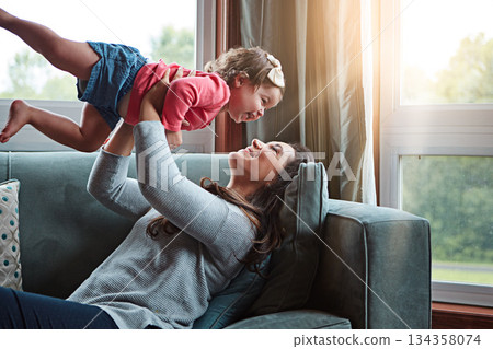 Happy, mom and lifting girl on sofa in home living room and relax, bonding and quality time together or mother, love and family happiness. Child, mommy and playing game on couch in house with smile Happy, mom and lifting girl on sofa in home living room and relax, bonding and quality time together or mother, love and family happiness. Child, mommy and playing game on couch in house with smile 134358074