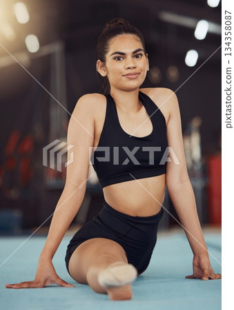 Dance or gymnastics stretching, sports health exercise and split training before a fitness workout. Portrait of a young woman gymnast or dancer before a sport performance or competition at a gym 134358087