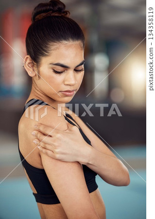 Injury, hurt and shoulder pain for a female athlete holding her painful arm at the gym. Active, fit and athletic woman suffering from muscle inflammation due to an exercise or workout 134358119