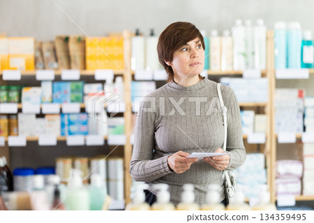 Woman with prescription looking for items in pharmacy 134359495