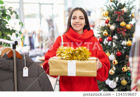 Girl with gift box in the interior of a clothing store during Christmas celebrations Girl with gift box in the interior of a clothing store during Christmas celebrations 134359607