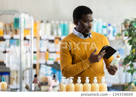 Man in glasses scans code on medicinal shampoo to check expiration date 134359609