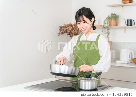 Young Asian woman in an apron cooking in the kitchen Young Asian woman in an apron cooking in the kitchen 134359815
