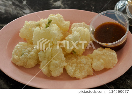 Close-up view of Cireng, crispy and chewy Indonesian fried tapioca starch snack (Aci digoreng), served hot on a pink melamine plate with spicy chili dipping sauce. Close-up view of Cireng, crispy and chewy Indonesian fried tapioca starch snack (Aci digoreng), served hot on a pink melamine plate with spicy chili dipping sauce. 134360077