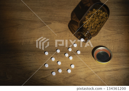 White pills spilled on a table and a brown opaque bottle White pills spilled on a table and a brown opaque bottle 134361200