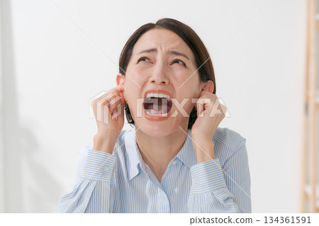 Woman covering her ears and screaming 134361591