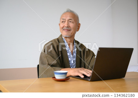 一位身穿浴衣的老人正在使用筆記型電腦 134362180