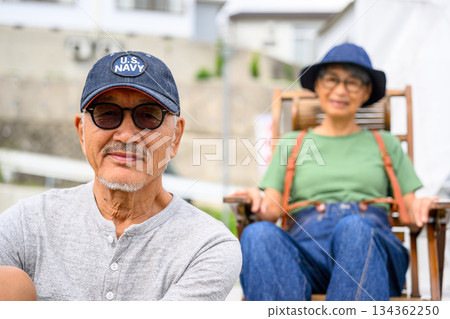 Husband wearing sunglasses and wife sitting in a chair [Photo courtesy of Oki Seaside Hotel Miyabi] 134362250