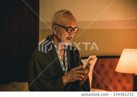 Senior man looking at smartphone in bedroom 134362252