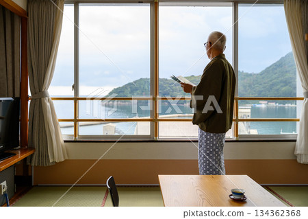 Senior man reading a tourist guide by the window 134362368