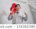 Worker holding a traffic cone, fist pump, warehouse 134362386