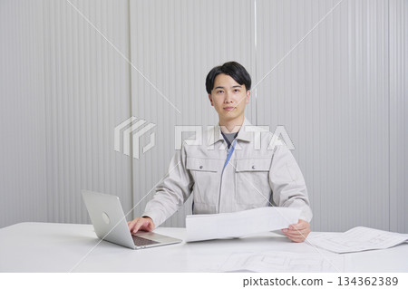 A man working at a construction company sitting with a blueprint, indoor portrait, looking at the camera 134362389