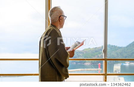 一個身穿浴衣的男人望著窗外的風景。 一個身穿浴衣的男人望著窗外的風景。 134362462